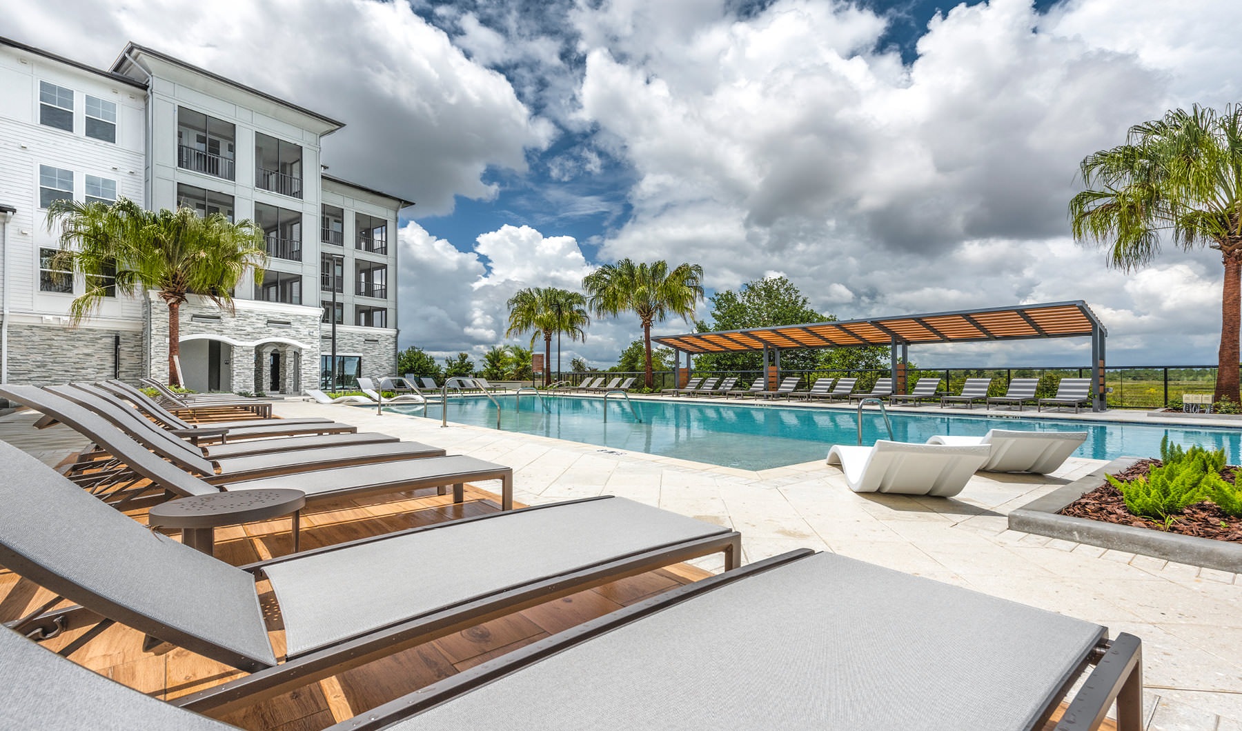 Reclining lounge chairs surround outdoor swimming pool next to lake at The Westerly